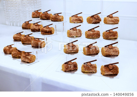 Desserts are arranged on stands at celebration event each dessert has piece of chocolate stick on top. Desserts are arranged on stands at celebration event each dessert has piece of chocolate stick on top. 140049856