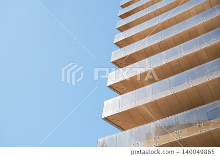 Modern high-rise residential building with glass facade against a clear blue sky. Modern high-rise residential building with glass facade against a clear blue sky. 140049865