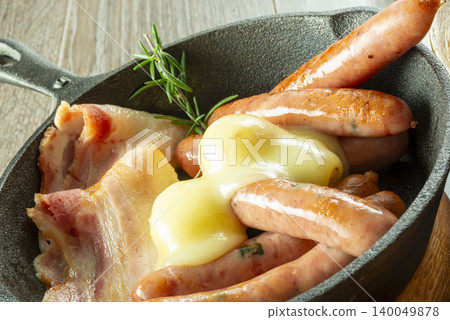 A delicious dish of sausage and bacon topped with cheese, cooked in a skillet. A delicious dish of sausage and bacon topped with cheese, cooked in a skillet. 140049878