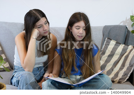 Horizontal picture of two teens girs looking at a music sheet together,enjoying leisure time and friendly bonding indoors Horizontal picture of two teens girs looking at a music sheet together,enjoying leisure time and friendly bonding indoors 140049904