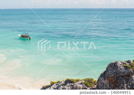 People vacationing on a small boat along the bright turquoise waters of the Caribbean Sea near Tulum, Mexico, enjoying a sunny day on a tropical beach holiday People vacationing on a small boat along the bright turquoise waters of the Caribbean Sea near Tulum, Mexico, enjoying a sunny day on a tropical beach holiday 140049951