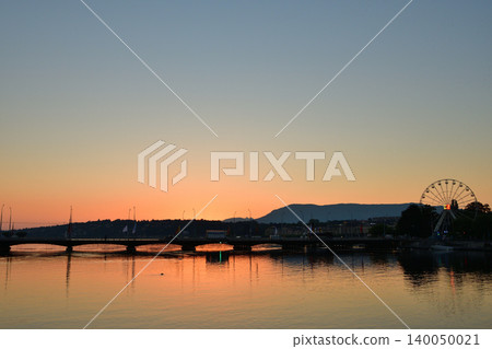Sunrise over Lake Geneva, viewed from the Rhone River in Geneva. Swiss landscape (August 16, 2022) Sunrise over Lake Geneva, viewed from the Rhone River in Geneva. Swiss landscape (August 16, 2022) 140050021