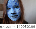 Master making aqua makeup. Face painting of a girl with a blue face. face painting kids child. 140050109