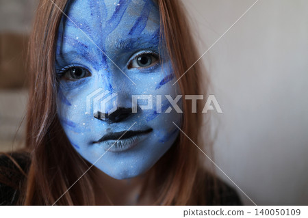 Master making aqua makeup. Face painting of a girl with a blue face. face painting kids child. 140050109