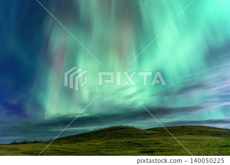 Vibrant green aurora borealis dances across a starry night sky over hills Vibrant green aurora borealis dances across a starry night sky over hills 140050225