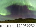 Vibrant green and purple aurora borealis dances across a starry night sky 140050232