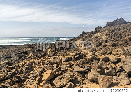 A sea view beyond a stark desert landscape on Lanzarote, capturing the islands raw volcanic beauty A sea view beyond a stark desert landscape on Lanzarote, capturing the islands raw volcanic beauty 140050252