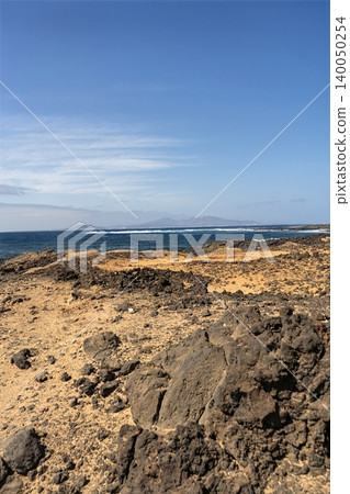 A sea view beyond a stark desert landscape on Lanzarote, capturing the islands raw volcanic beauty A sea view beyond a stark desert landscape on Lanzarote, capturing the islands raw volcanic beauty 140050254