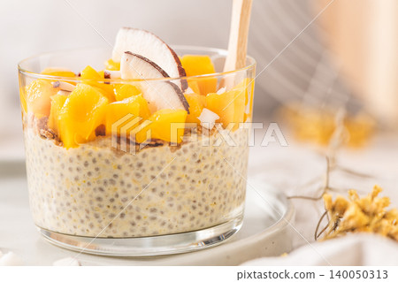 Creamy chia seed pudding in a glass topped with vibrant mango cubes and fresh coconut slices for a healthy breakfast or tropical vegan dessert served on a neutral aesthetic background with no marks Creamy chia seed pudding in a glass topped with vibrant mango cubes and fresh coconut slices for a healthy breakfast or tropical vegan dessert served on a neutral aesthetic background with no marks 140050313