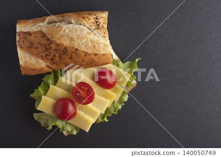 Sandwich with cheese, tomatoes, and greens on a granite floor. Sandwich with cheese, tomatoes, and greens on a granite floor. 140050749