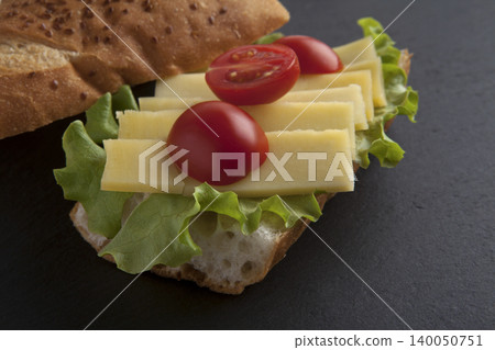 Sandwich with cheese, tomatoes, and greens on a granite floor. Sandwich with cheese, tomatoes, and greens on a granite floor. 140050751