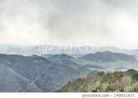 A distant view from the grounds of Engyo-ji Temple on Mount Shosha, showing the city of Himeji and the surrounding mountains in early spring with snow falling (Himeji City, Hyogo Prefecture). A distant view from the grounds of Engyo-ji Temple on Mount Shosha, showing the city of Himeji and the surrounding mountains in early spring with snow falling (Himeji City, Hyogo Prefecture). 140051631