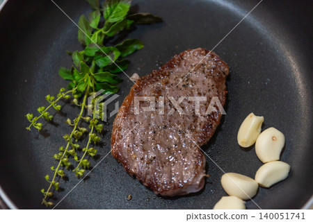 Juicy pan seared steak cooked fresh garlic basil skillet highlighting gourmet cuisine rich flavor home cooking excellence 140051741