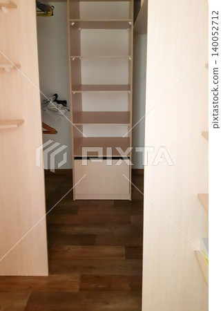 Interior view of a modern closet with wooden shelves and a drawer, showcasing organized storage space and a clean, minimalist design Interior view of a modern closet with wooden shelves and a drawer, showcasing organized storage space and a clean, minimalist design 140052712
