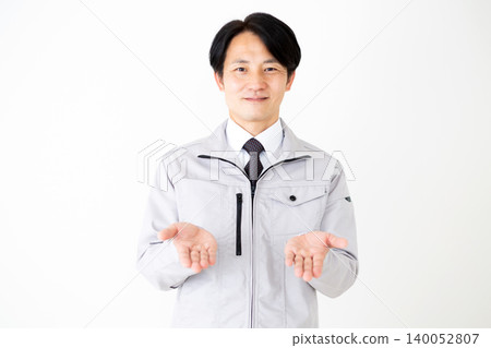 A middle-aged businessman in gray work clothes recommending a product against a white background. A middle-aged businessman in gray work clothes recommending a product against a white background. 140052807