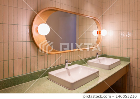 Wood-framed mirror in bathroom with lights and sink with silver faucet and socket. Wood-framed mirror in bathroom with lights and sink with silver faucet and socket. 140053210