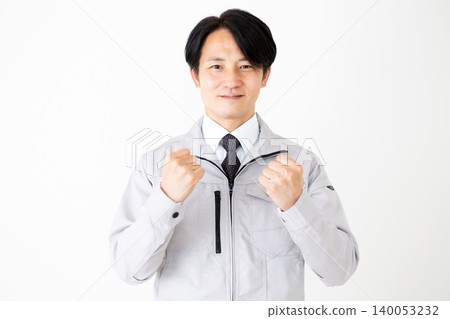 A middle-aged businessman in gray work clothes makes a victory pose against a white background. 140053232