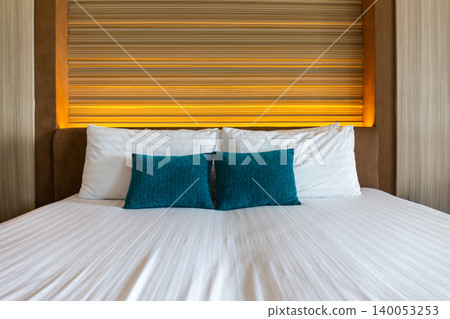 Blue and white pillows on the bed in a modern bedroom decorated with wood and lights. Blue and white pillows on the bed in a modern bedroom decorated with wood and lights. 140053253