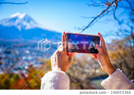Woman uses a smartphone to take pictures of Mount Fuji in autumn. 140053368