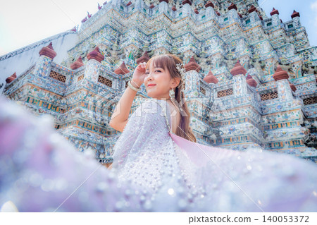 Close up of a young woman wearing traditional Thai dress with accessories standing at Wat Arun, a popular place for tourists around the world. Bangkok Thailand 140053372
