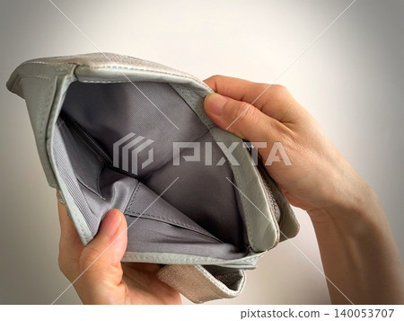 Close-up of a woman's hands as she opens an empty wallet. 140053707