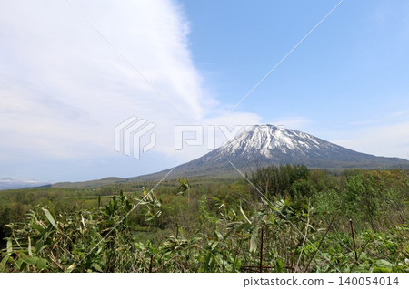 May in Hokkaido: Niseko, Kutchan, Ezo Fuji, Mount Yotei, Mount Yotei with lingering snow, the majestic mountain of Hokkaido, shining brightly against the blue sky. May in Hokkaido: Niseko, Kutchan, Ezo Fuji, Mount Yotei, Mount Yotei with lingering snow, the majestic mountain of Hokkaido, shining brightly against the blue sky. 140054014