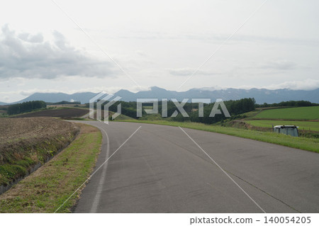 北海道美瑛寬闊的公路、十勝山脈以及九月初秋的鄉村全景。 北海道美瑛寬闊的公路、十勝山脈以及九月初秋的鄉村全景。 140054205