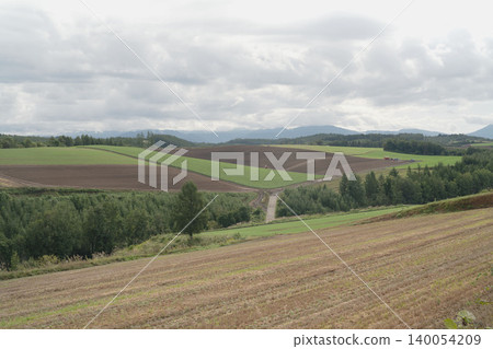 The patchwork hills and green fields of Biei, Hokkaido, with the Tokachi Mountain Range in the distance, a rural landscape in early September. The patchwork hills and green fields of Biei, Hokkaido, with the Tokachi Mountain Range in the distance, a rural landscape in early September. 140054209