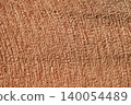 Background image of a light orange fabric pattern illuminated by sunlight. 140054489