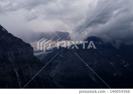 瑞士阿爾卑斯山的冰川和雲霧繚繞的岩石山峰,壯麗而低調的山景,八月盛夏。 瑞士阿爾卑斯山的冰川和雲霧繚繞的岩石山峰,壯麗而低調的山景,八月盛夏。 140054568