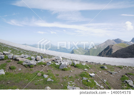瑞士阿爾卑斯山的雪原和綠色高原,遠處的山脈-八月中旬瑞士阿爾卑斯山的壯麗景色。 瑞士阿爾卑斯山的雪原和綠色高原,遠處的山脈-八月中旬瑞士阿爾卑斯山的壯麗景色。 140054578