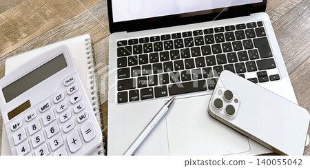 A simple workspace with a laptop, smartphone, and calculator. A simple workspace with a laptop, smartphone, and calculator. 140055042