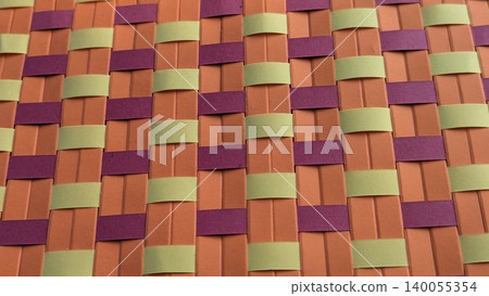 A vibrant, macro shot of woven paper strips creating a checkered pattern. The colors are a combination of orange, dark purple-maroon, light olive-green. A vibrant, macro shot of woven paper strips creating a checkered pattern. The colors are a combination of orange, dark purple-maroon, light olive-green. 140055354