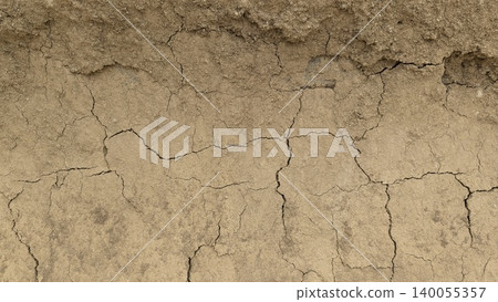 A detailed close-up of rough, textured earth showing a mix of fine dirt, gravel, rocks. The surface transitions from dark gray on the left to light brown on the right. A detailed close-up of rough, textured earth showing a mix of fine dirt, gravel, rocks. The surface transitions from dark gray on the left to light brown on the right. 140055357