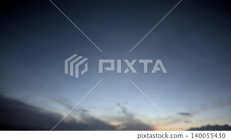 The image captures a deep blue twilight sky. Wispy clouds linger near the darkened horizon. A faint orange glow emerges from the sunrise. The atmosphere appears calm, vast, silent. High-altitude The image captures a deep blue twilight sky. Wispy clouds linger near the darkened horizon. A faint orange glow emerges from the sunrise. The atmosphere appears calm, vast, silent. High-altitude 140055430