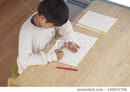 A boy doing his homework in a brightly lit living room. A boy doing his homework in a brightly lit living room. 140055706