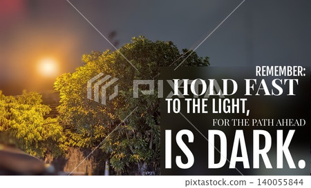 A tree's silhouette is cast against a bright street light at night, featuring the quote, "HOLD FAST TO THE LIGHT, FOR THE PATH AHEAD IS DARK." This image inspires perseverance hope through difficulty. A tree's silhouette is cast against a bright street light at night, featuring the quote, "HOLD FAST TO THE LIGHT, FOR THE PATH AHEAD IS DARK." This image inspires perseverance hope through difficulty. 140055844