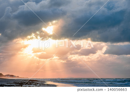 Beautiful sunset over the beach with dramatic clouds and shimmering ocean waves 140056663