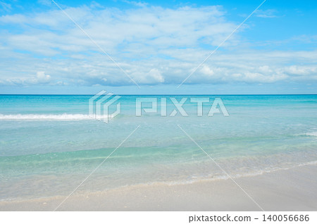 Calm ocean waves gently lap on the sandy shore under a bright blue sky Calm ocean waves gently lap on the sandy shore under a bright blue sky 140056686