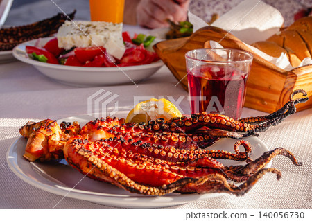 Grilled octopus served with lemon, accompanied by  drinks. 140056730