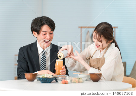 一對夫婦在晚上喝酒；妻子正在倒啤酒；一位女士。 140057108