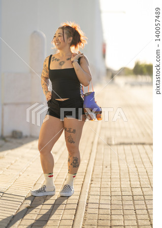 Young woman smiling carrying roller skates on shoulder Young woman smiling carrying roller skates on shoulder 140057489