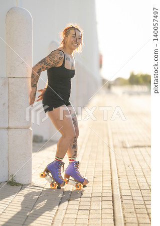 Tattooed young woman smiling wearing roller skates Tattooed young woman smiling wearing roller skates 140057497