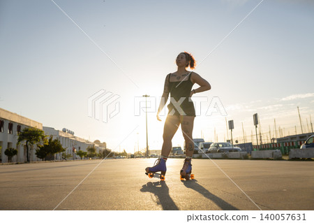 Confident young woman posing on roller skates at sunset 140057631