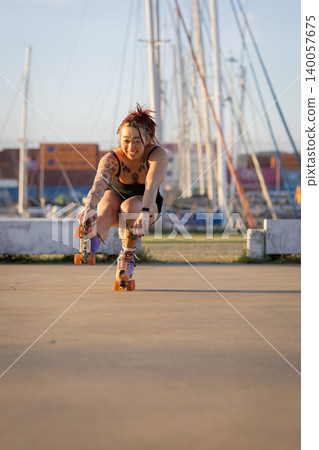 Tattooed young woman roller skating outdoors at sunset Tattooed young woman roller skating outdoors at sunset 140057675