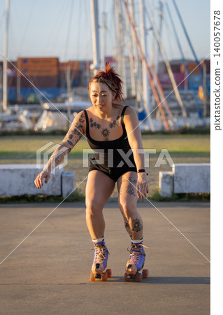 Tattooed woman happily roller skating in urban marina Tattooed woman happily roller skating in urban marina 140057678