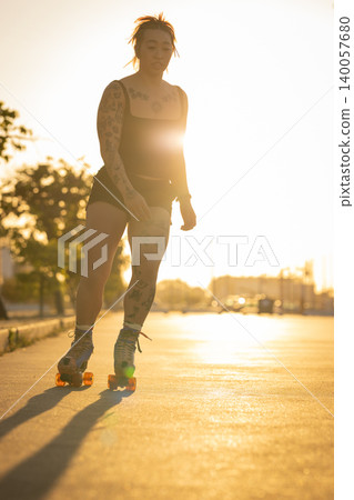 Tattooed woman enjoying street roller skating at sunset Tattooed woman enjoying street roller skating at sunset 140057680