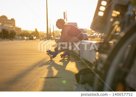 Woman tying roller skate laces on urban street sunset 140057752