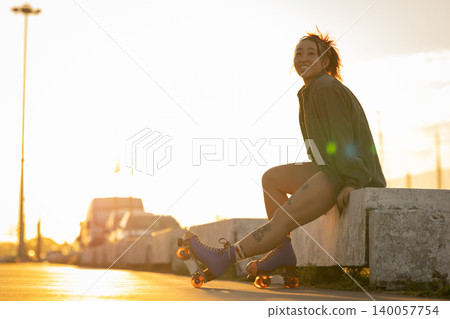 Young woman smiling while roller skating at sunset Young woman smiling while roller skating at sunset 140057754