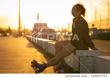 Young woman relaxing with roller skates during golden hour Young woman relaxing with roller skates during golden hour 140057755